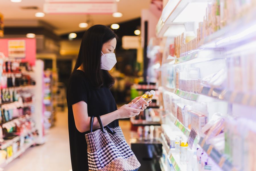 woman looking at shampoo in supermarket