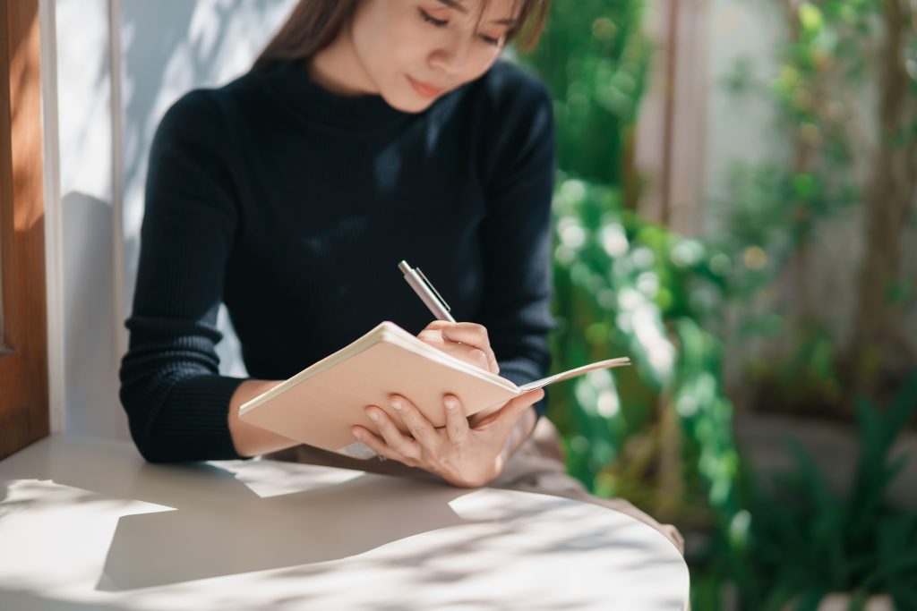 a woman writing on her journal